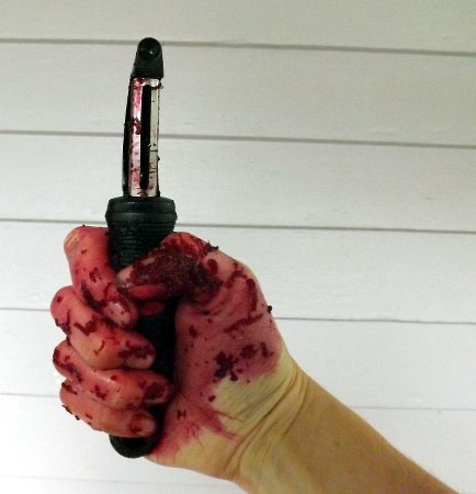 a beet red hand holding a peeler