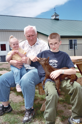 Caleb, Grandpa, and Anna with a baby goat