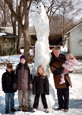 The kids pose in front of another big snowman